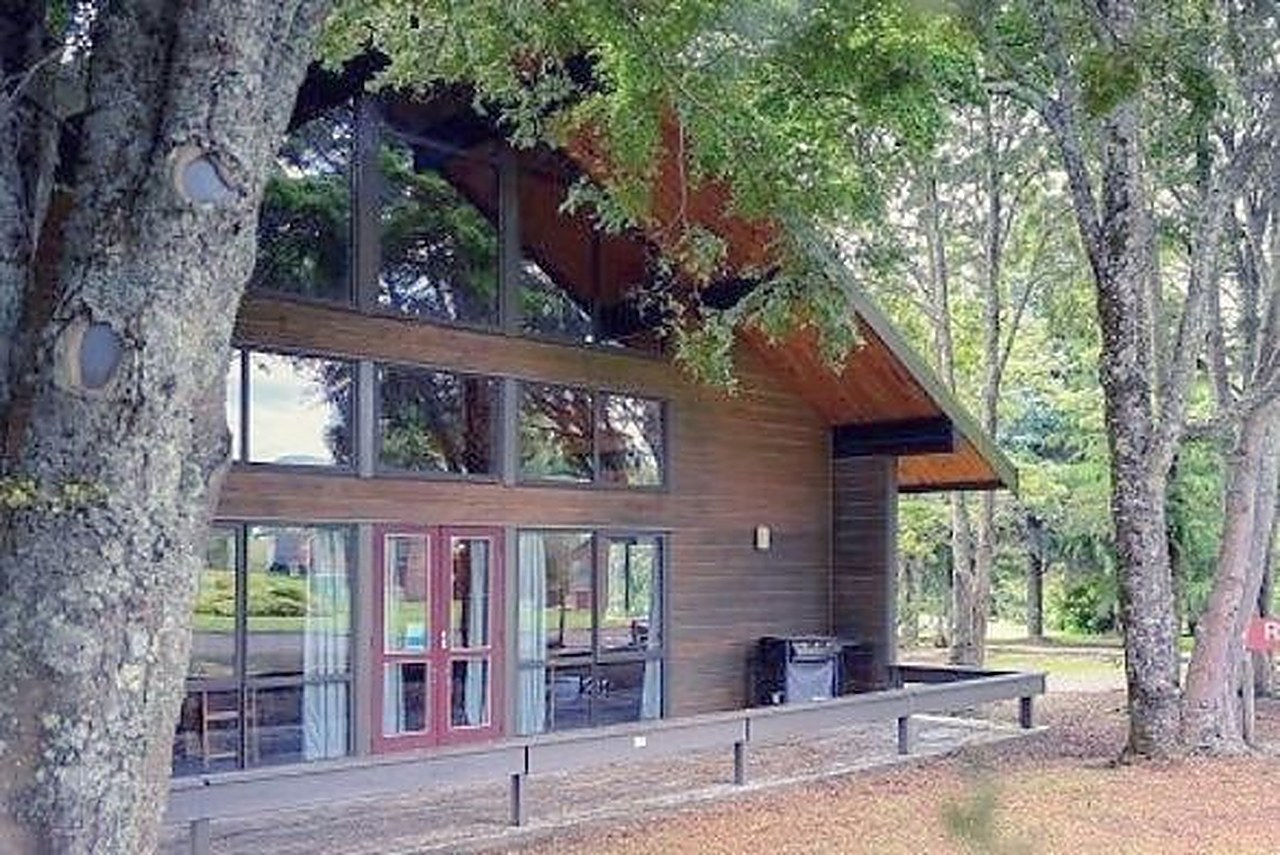 Turoa Lodge, a two-storey timber and glass building among trees at Ohakune